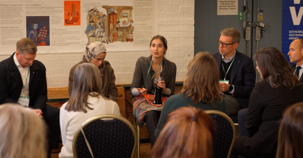 Julieta Martinez in a discussion. Holding a water bottle. On her right side sits the CEO of Port of Gothenburg Göran Eriksson